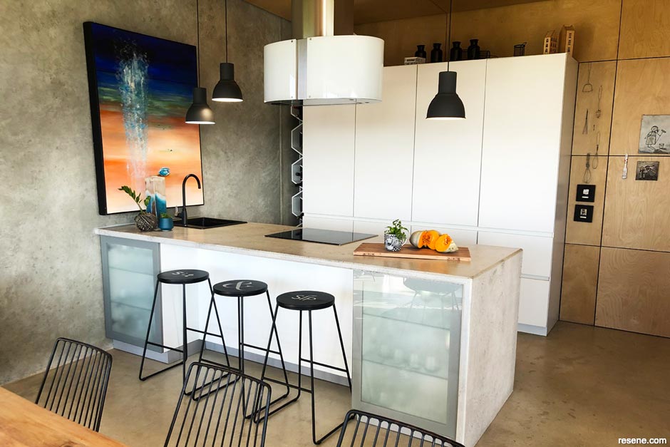 An industrial kitchen with faux concrete walls and benchtop