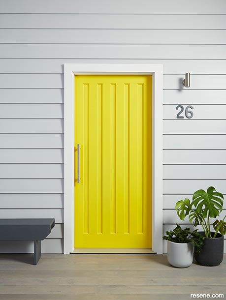 Grey exterior weatherboards with a bright yellow front door