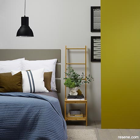 A grey bedroom with one yellow toned wall