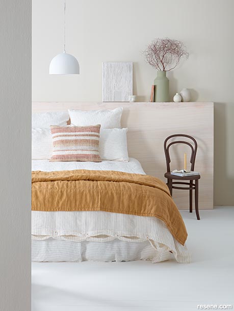 A pale bedroom with a caramel throw on the bed