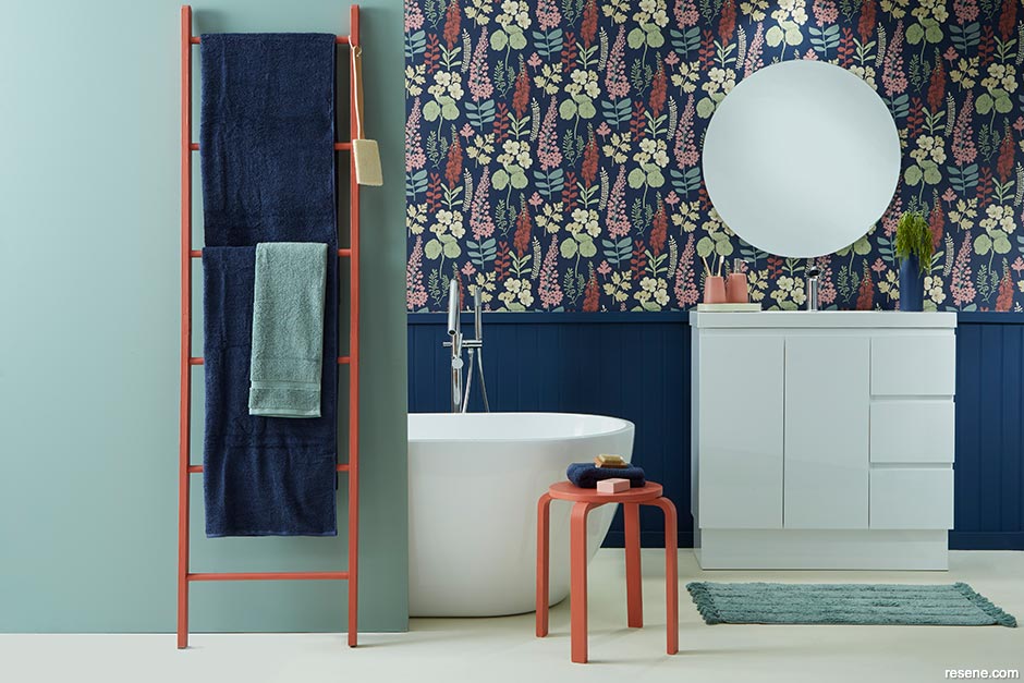 A bathroom with on-trend floral wallpaper and coral coloured accessories