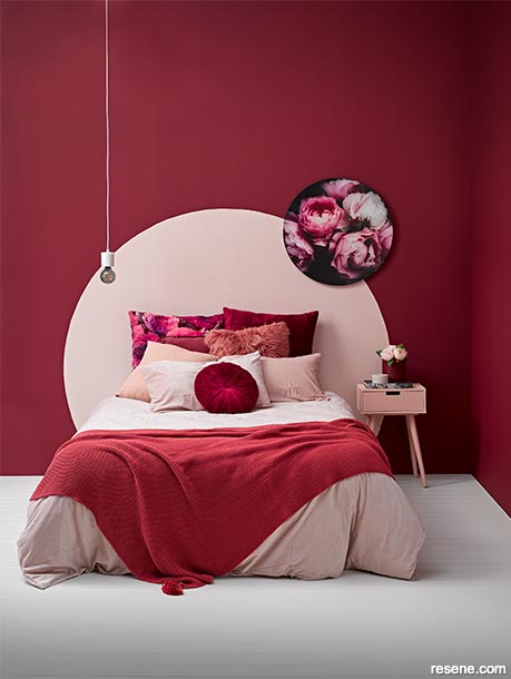 A deep red bedroom with a dusky pink headboard