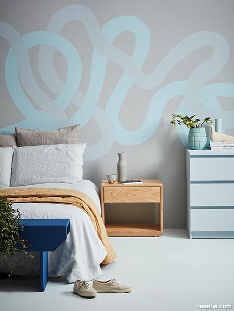 A bedroom with a blue swirly wave mural