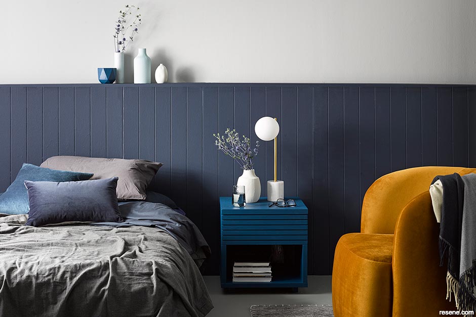 A bedroom with dark blue tongue-and-groove panelling