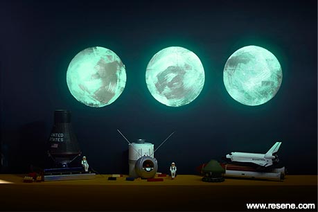A bedroom moon mural glowing at night