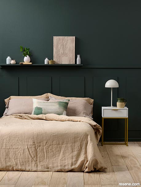 A bedroom with forest green walls and whitewashed floors