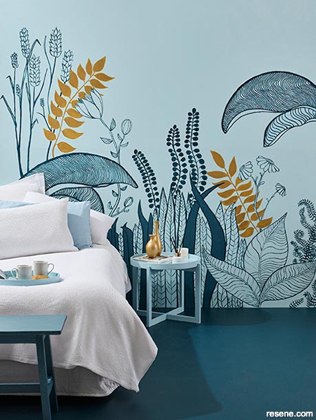 A blue bedroom with a nature inspired wall mural