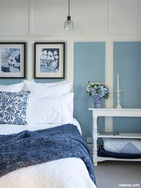 A blue and white bedrrom with a suble floral wallpaper