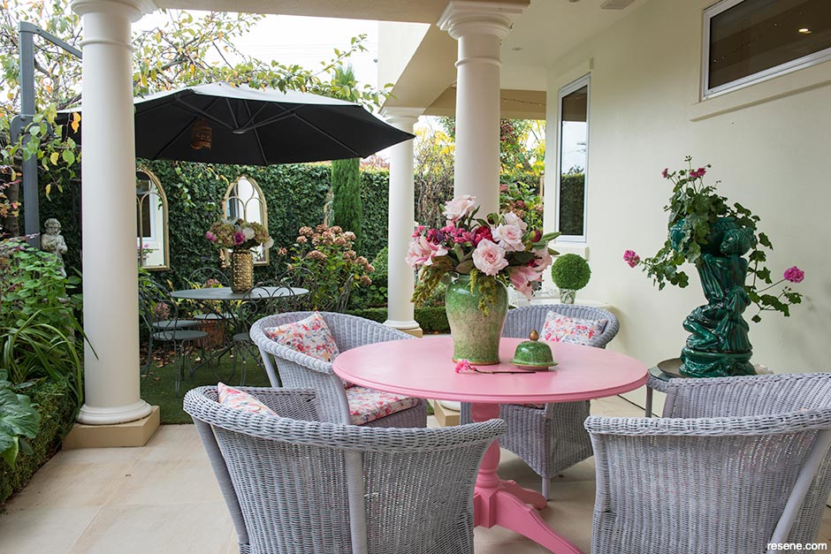 A pink outdoor table picks up the colour of the roses