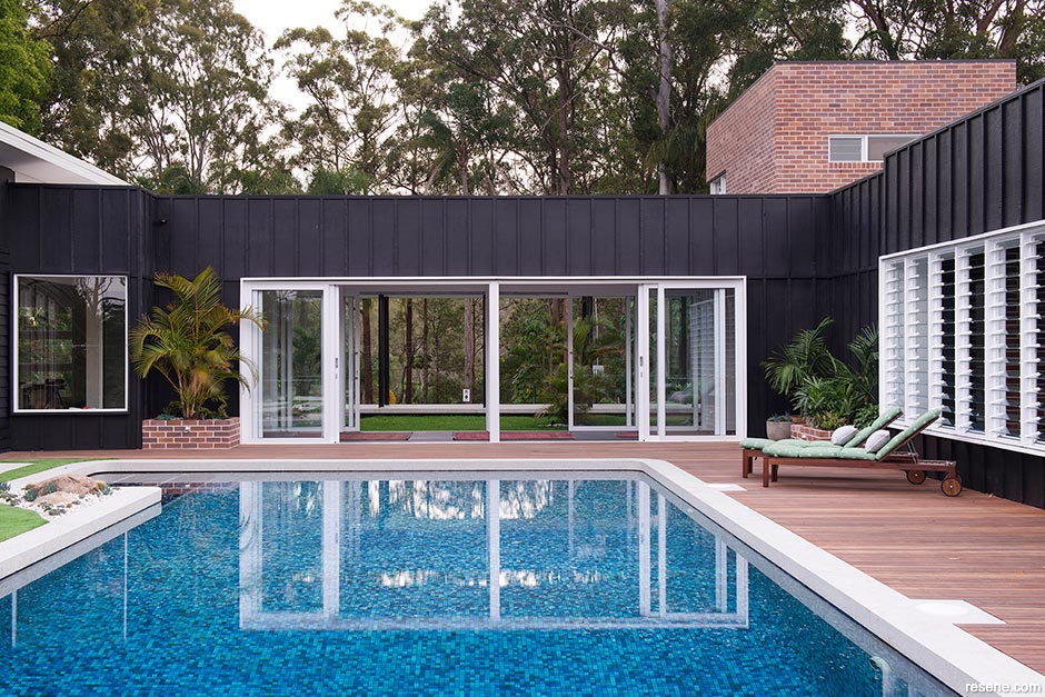 A mosaic-style pool against a black home exterior