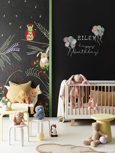 A nursery with a wall mural and chalkboard wall