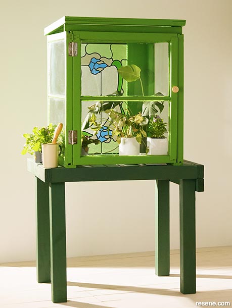 A DIY mini glasshouse made from a repurposed stain glass window