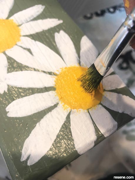 Painting the daisy centres on a picnic table